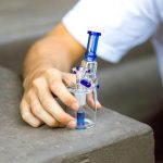 person in white long sleeve shirt holding blue and silver e cigarette