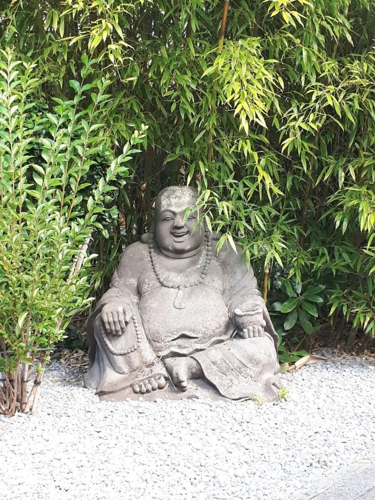 Stone Buddha statue surrounded by lush green bamboo, embodying peace and spirituality.